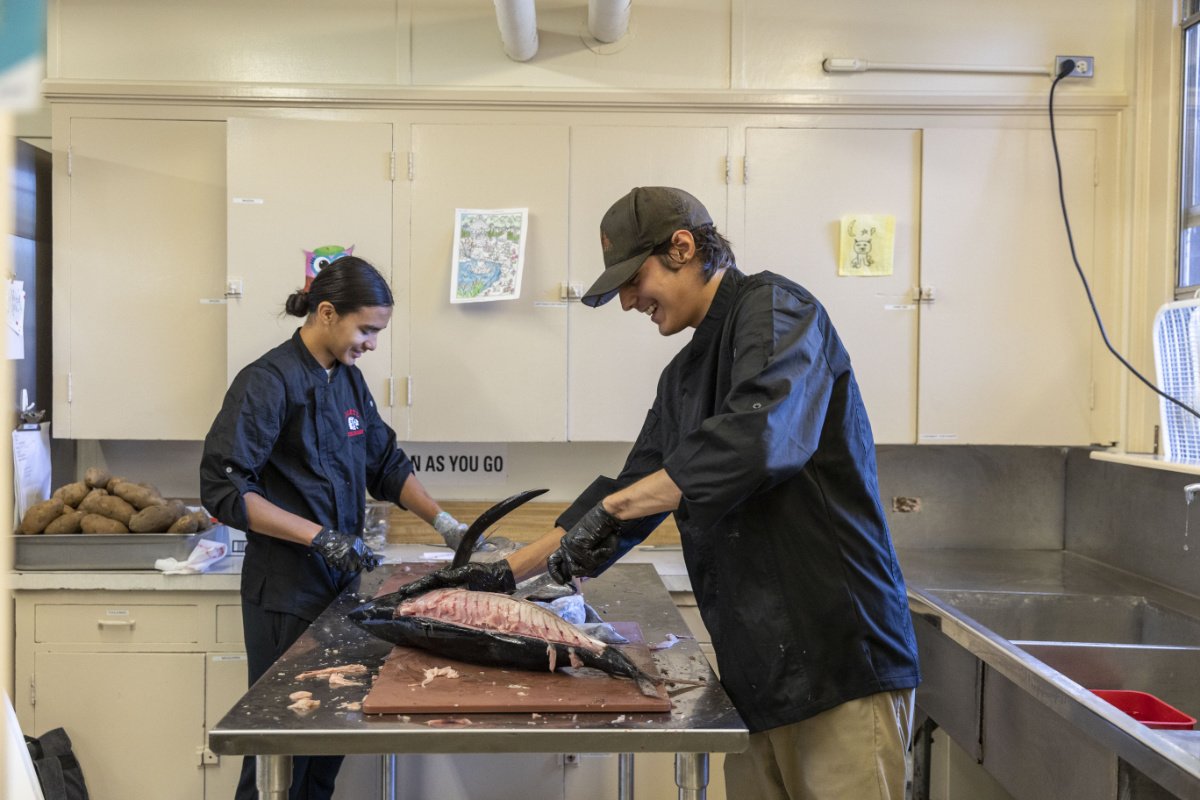 Des étudiants du programme culinaire de la Siletz Valley School dépecent un saumon pêché par une tribu. (Crédit photo : Rachelle Hacmac)