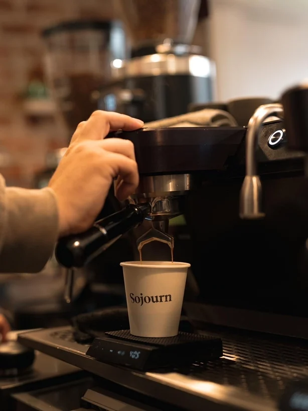 Un barista tire un shot d'espresso devant une machine à café